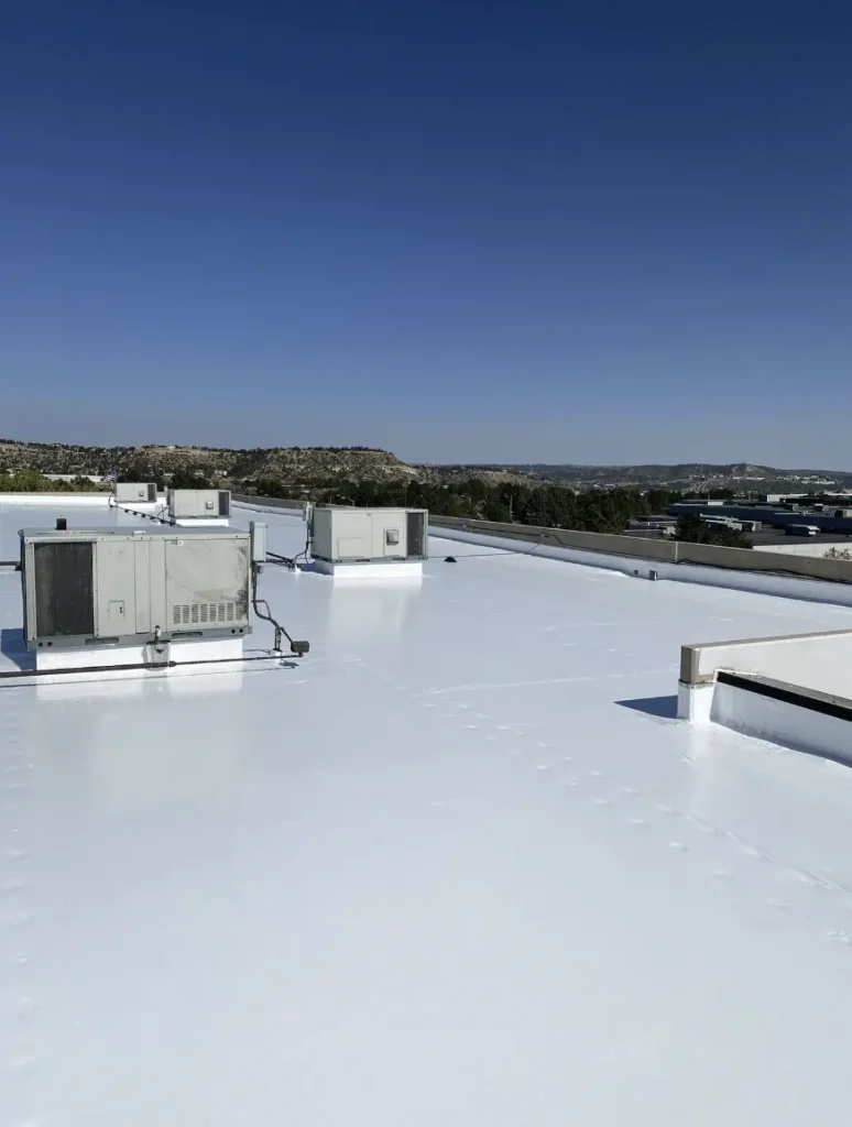 Finished white coated commercial flat roof under a clear blue sky