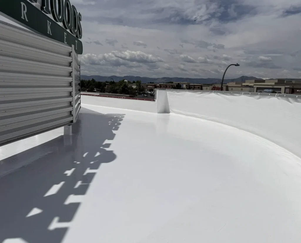 Finished white flat roof coating along a curved rooftop wall