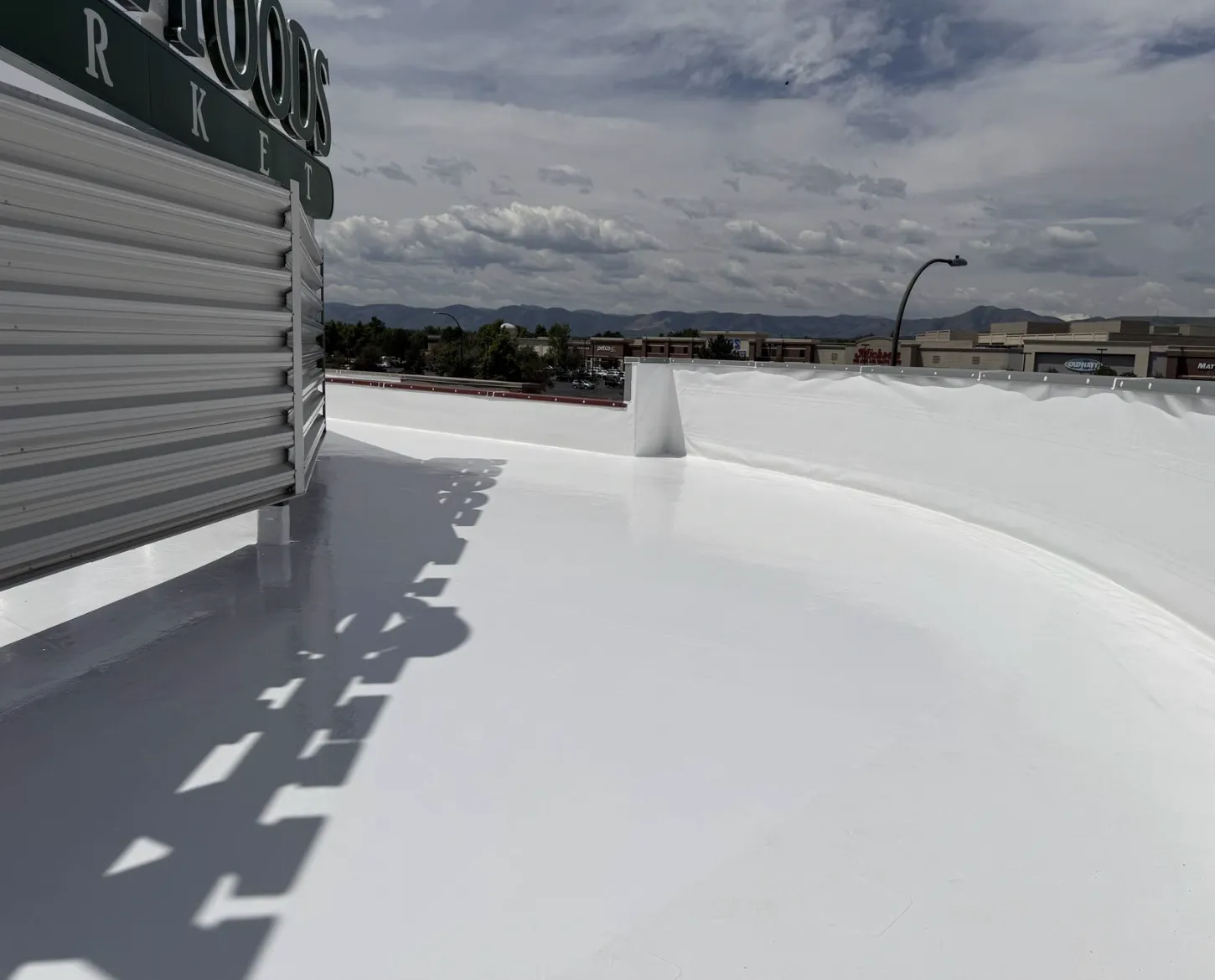 Finished white flat roof coating along a curved rooftop wall