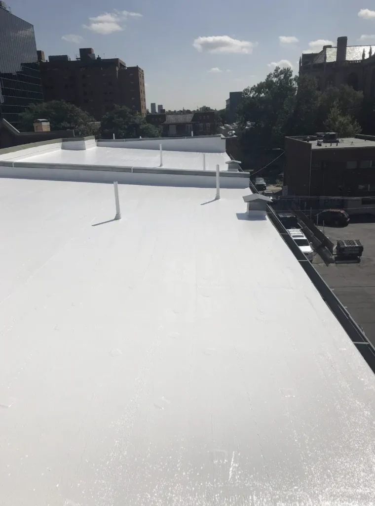Coated white flat roof edge with city buildings in the background