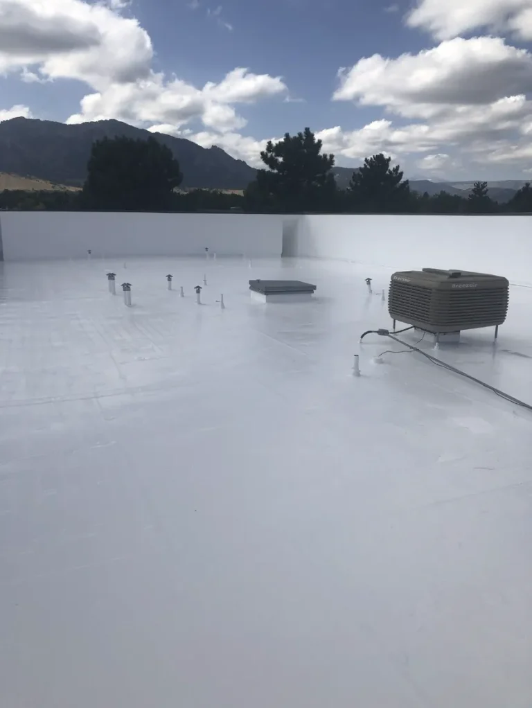 White coated flat roof with HVAC equipment and foothills beyond