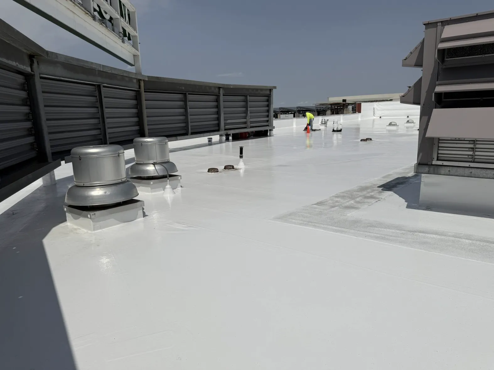 Coated white flat roof with rooftop mechanical units and exhaust fans