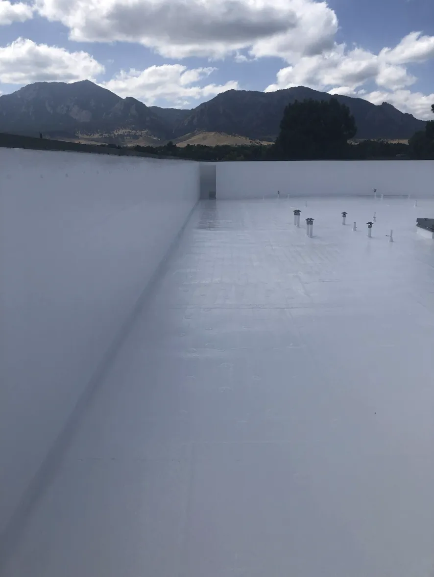 Seamless white roof coating on a flat roof with Colorado foothills in the background