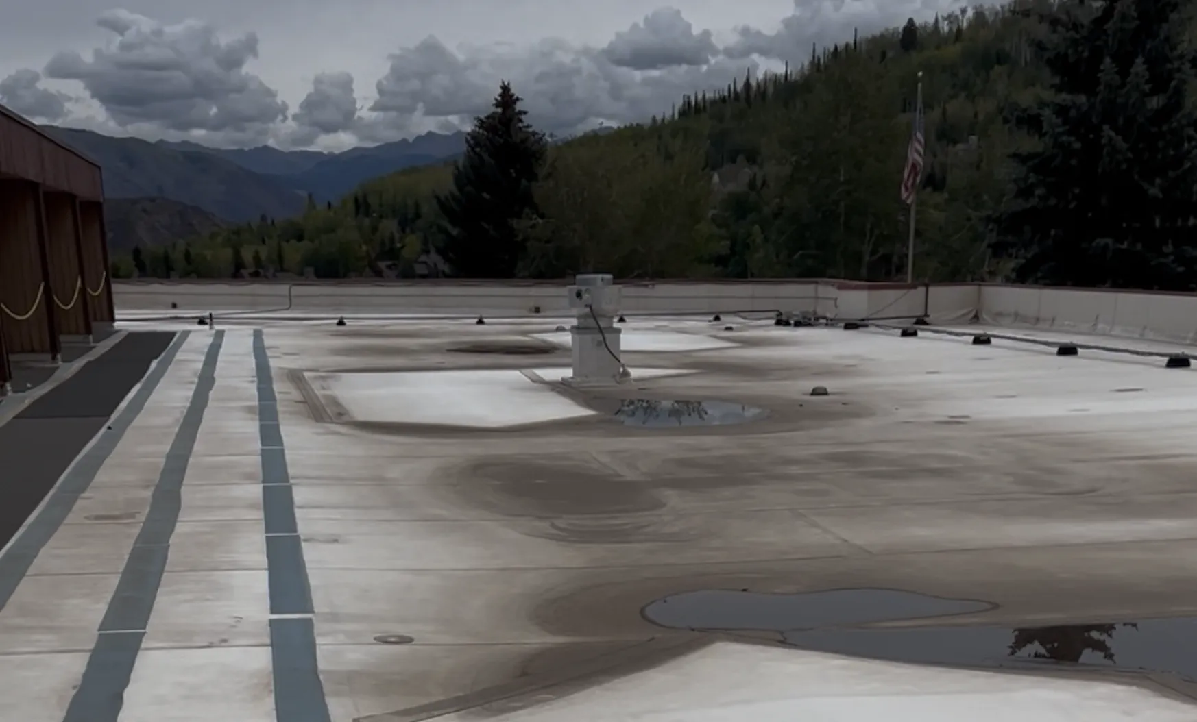 Aged commercial flat roof with ponding water and worn membrane before restoration