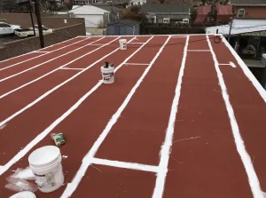 Crew applying red primer and white seam treatment on a commercial flat roof