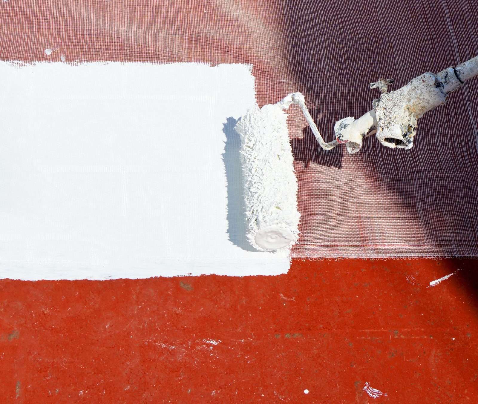 Roller applying a white waterproof coating on a flat roof