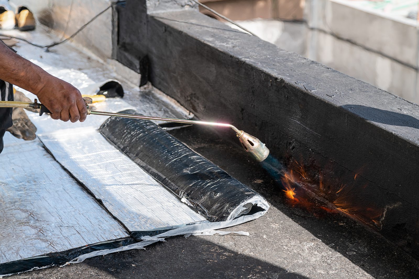 Roofer installing torch-down membrane on a commercial flat roof