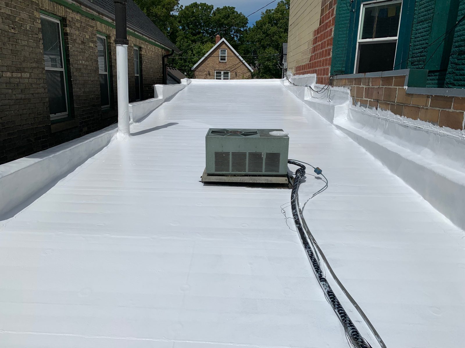 Silicone roof coating applied over a flat membrane roof
